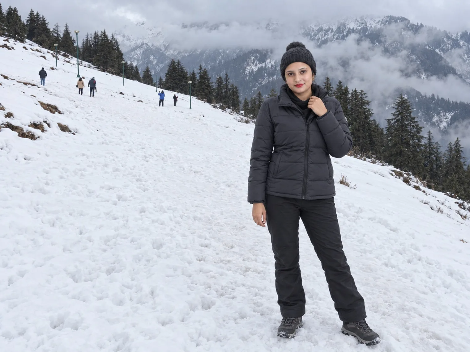Vandana standing alone on a wide snow-covered slope in January 2026, a few people walking far up the hill.